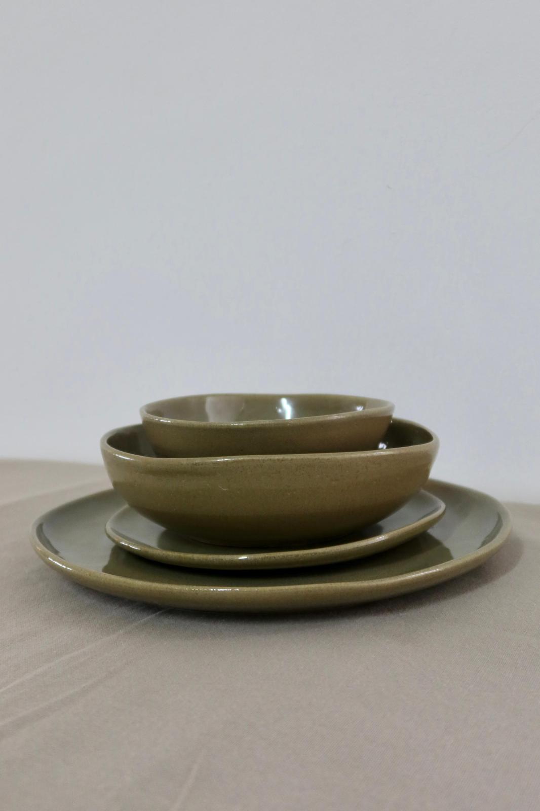 Das 16-teilige Keramik-Set von Gwen's Pottery — Teller und Schüsseln gestapelt auf Leinenstoff